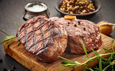 grilled beef steaks with spices on wooden cutting board