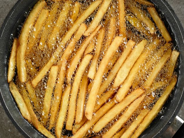 frying french fries in a pan with oil, top view